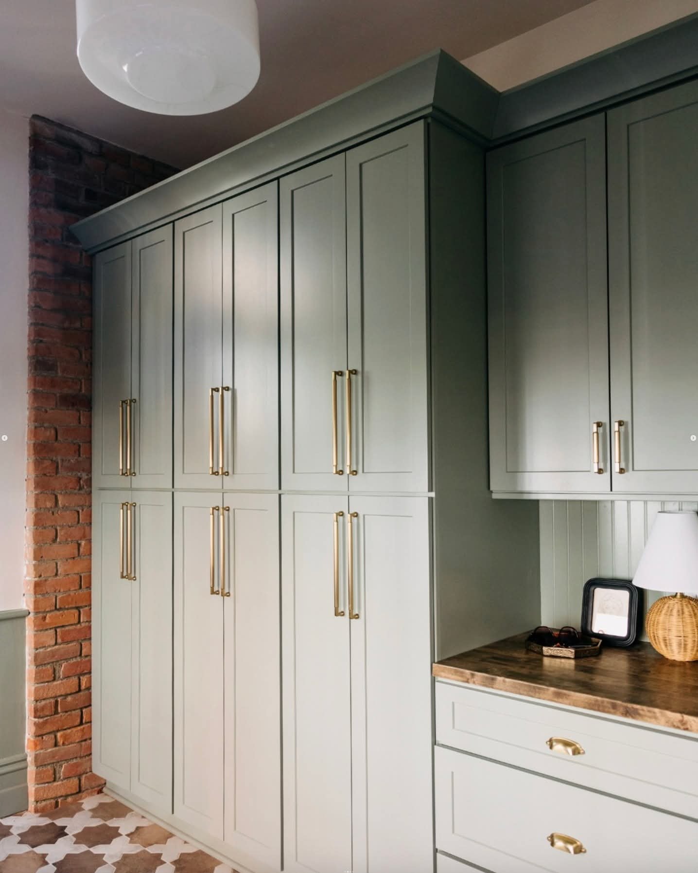 Sage built-in cabinetry with brass hardware by PrestigeCore